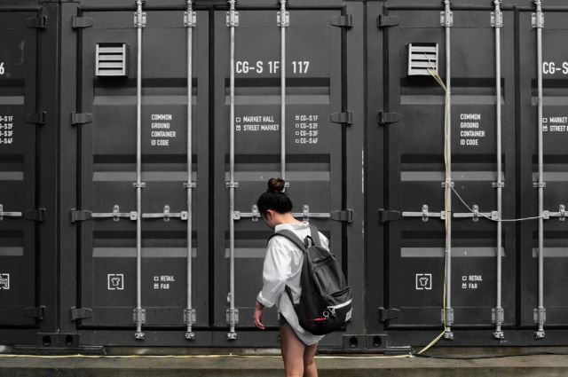 A person standing in front of large black storage containers, representing one of the options available when renting storage in Dubai