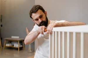 Man in a white shirt disassembling a bed with a screwdriver