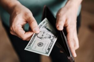 Person holding a $50 bill from their wallet.