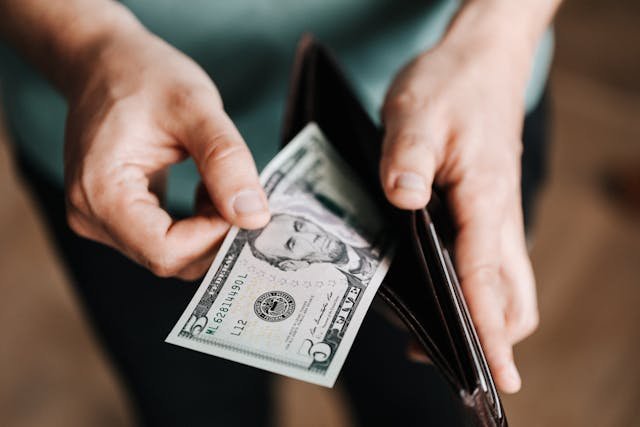Person holding a $50 bill from their wallet.