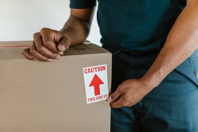 Person checking a moving box labeled "Caution: This Side Up" with a focus on the label.