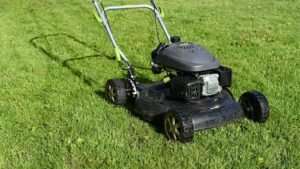 Gas push lawn mower on grass ready to be winterized before winter storage